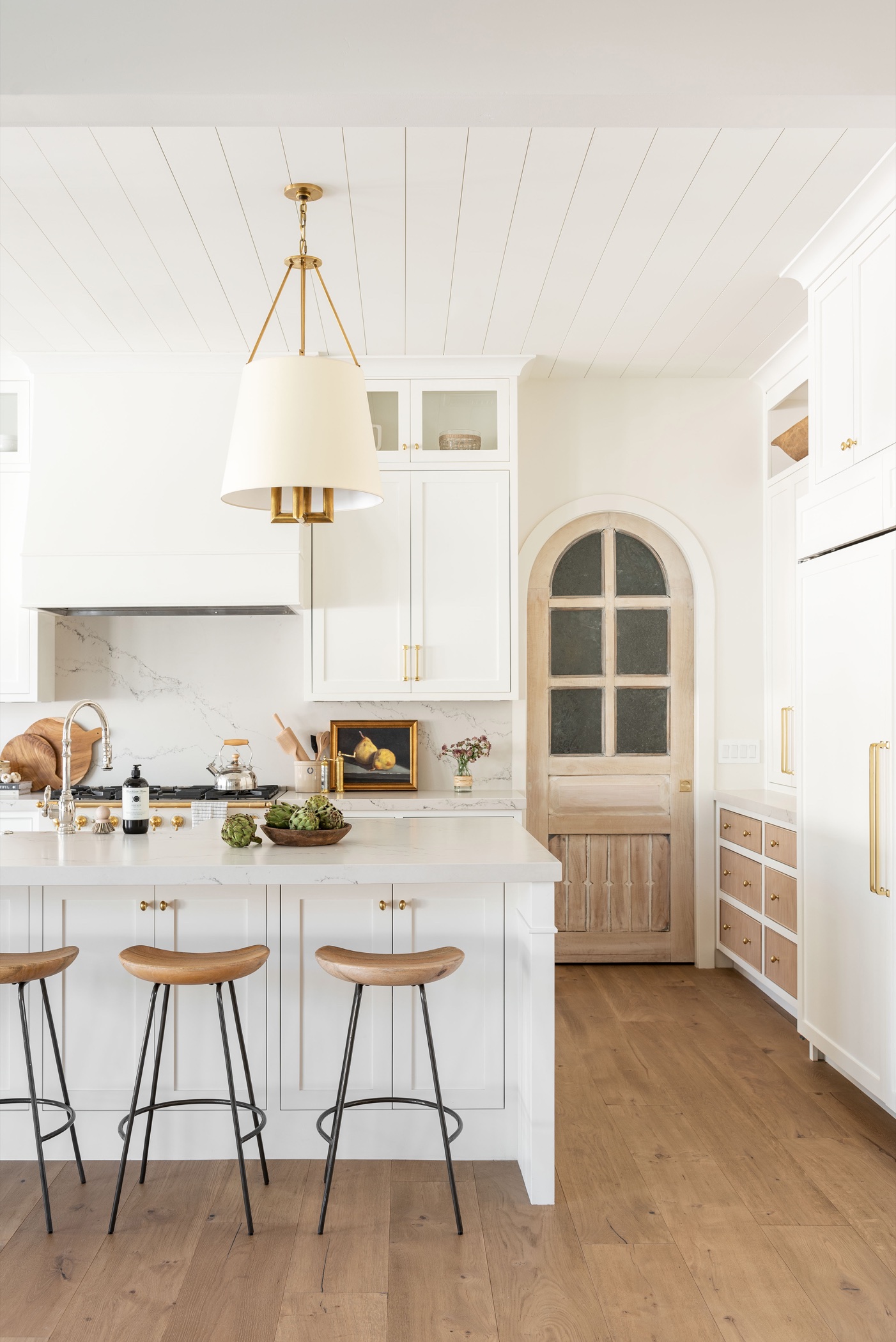 White kitchen with an arched wood pantry door at Calle Rosa